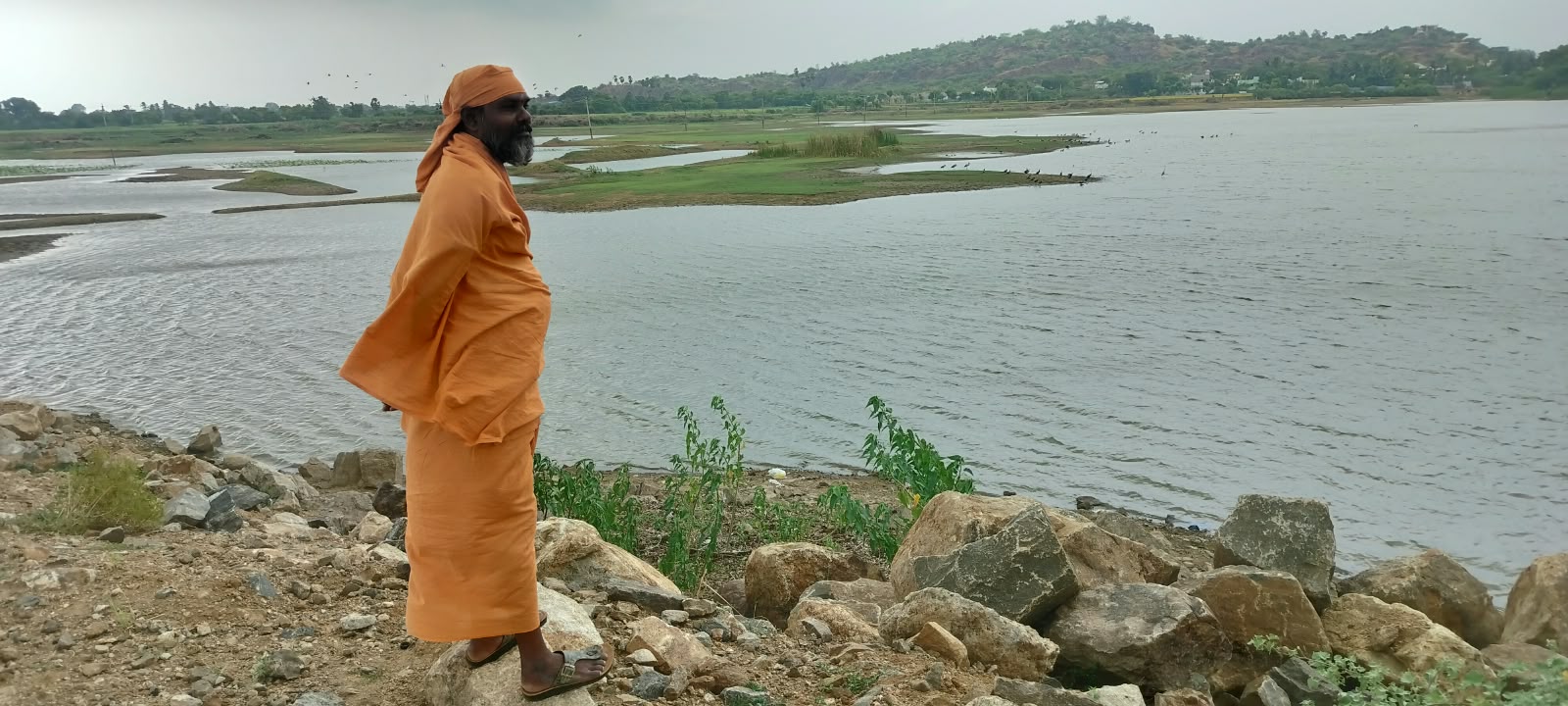 Mahaguru Samasthanam standing beside a broad, tranquil lake