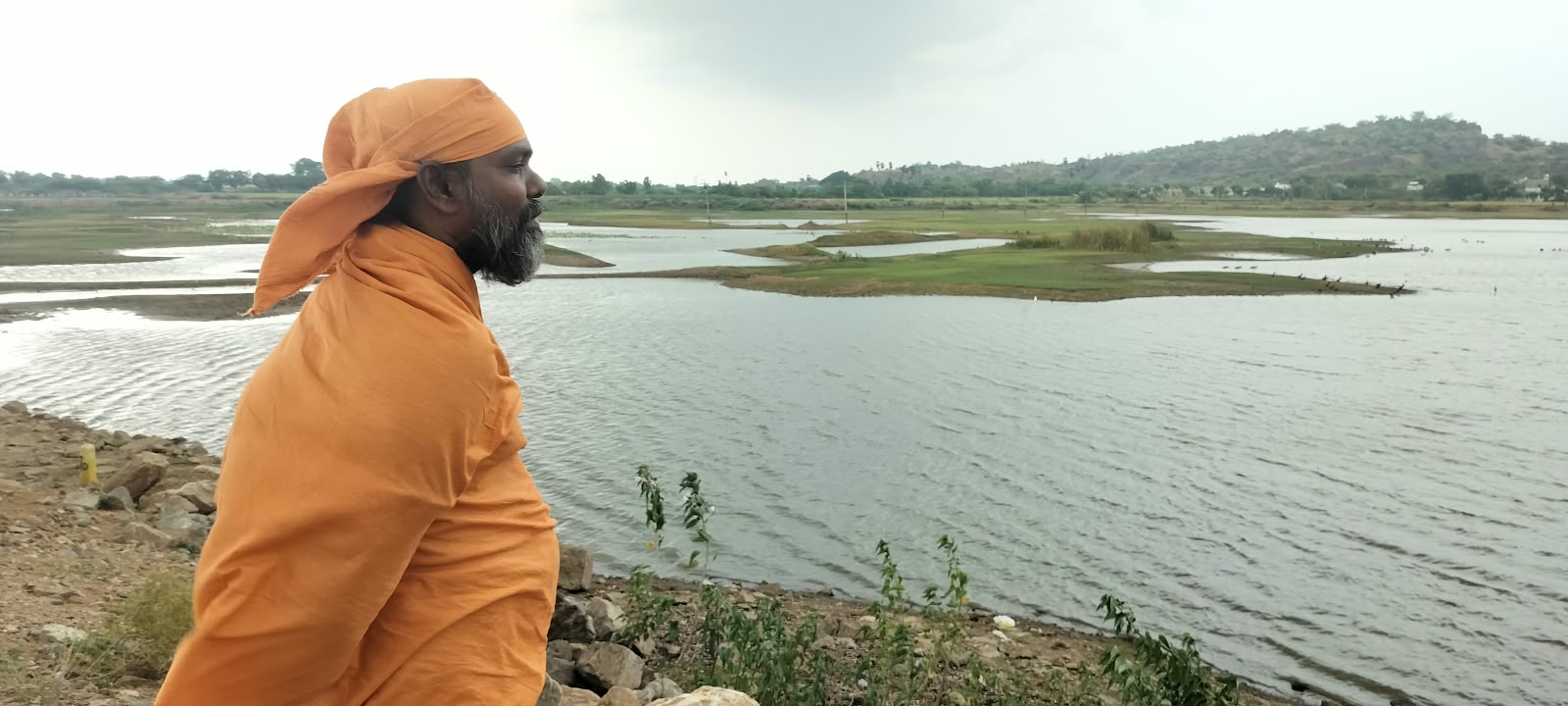 Mahaguru Datta Vanam in saffron robes by the waters